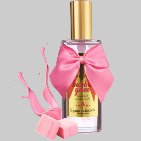 Bottle of bijoux indiscrets bubble gum warming massage oil with a pink bow and pink liquid splash on a light grey background